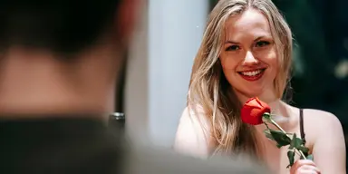 Kvinna på dejt med ros i handen – symboliserar den växande trenden att investera i professionell dejtingcoachning för att hitta en seriös relation.