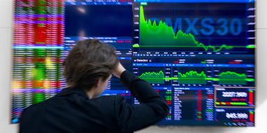 Man framför skärm med fallande aktiekurser på Stockholmsbörsen.