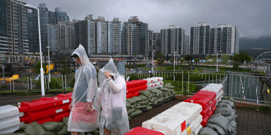 Två personer promenerar i Hong Kong under oväderssäsongen.
