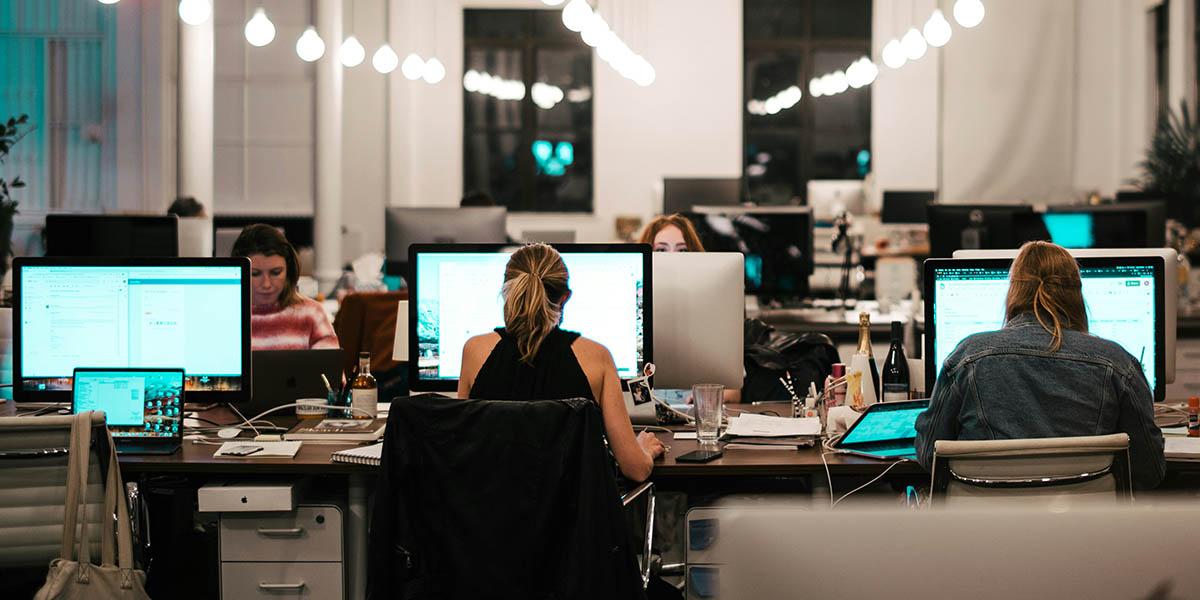 En bild på en kontorsmiljö där några kvinnor sitter och arbetar framför sina datorer.