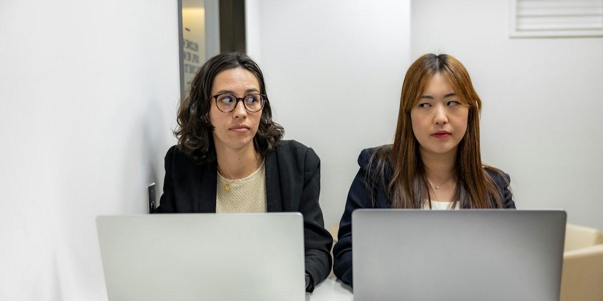 två kvinnor stirrar på varandra på en arbetsplats.