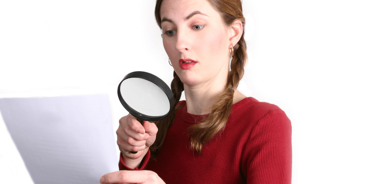 Kvinna granskar det finstilta efter kryphål med förstoringsglas.