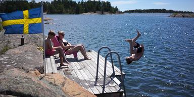 Bild på familj som badar i Sverige. Grekland är för varmt och Sverige lockar med ett kyligare klimat.