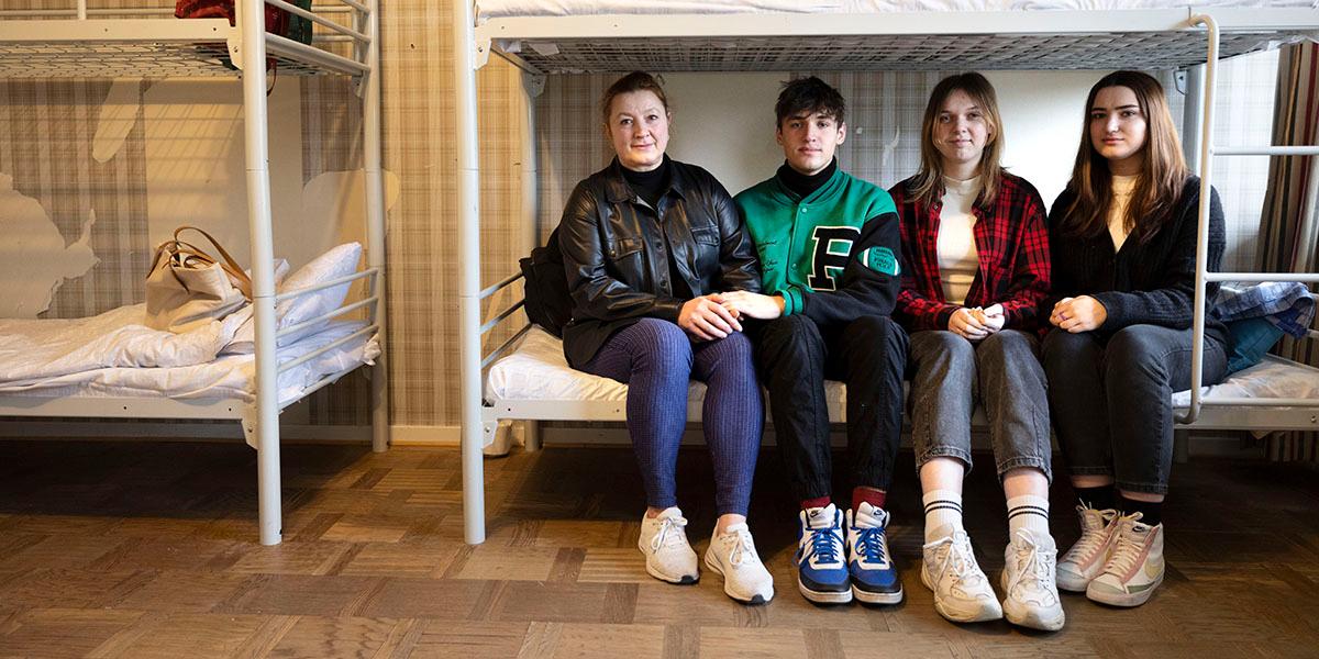 Fyra stycken ukrainska flyktingar sitter på en säng i en flyktingförläggning i Sverige.